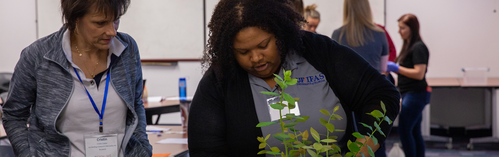 phD candidate Crystal Conner works with a guest on a plant